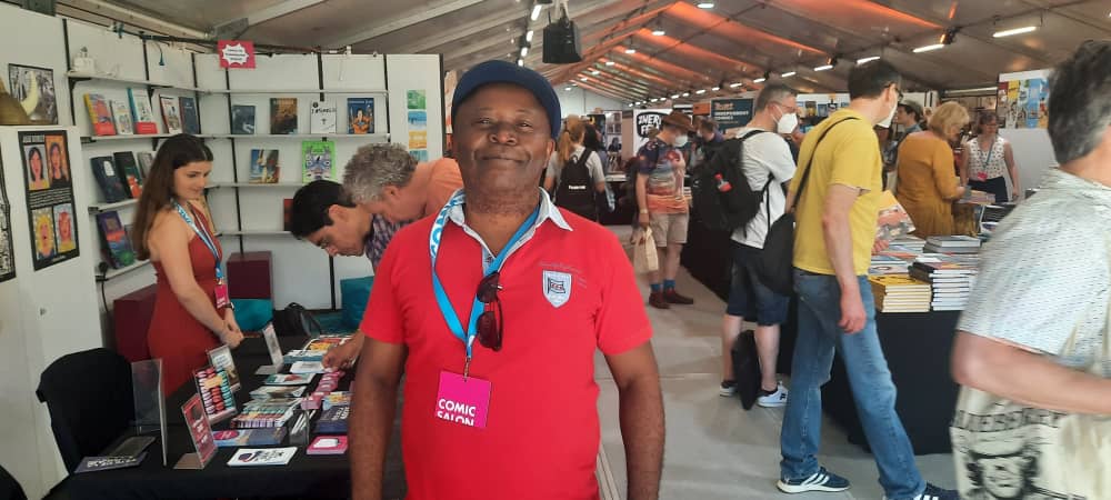 Thembo Kash posant devant des stands au Comic Salon d’Erlangen (DR)