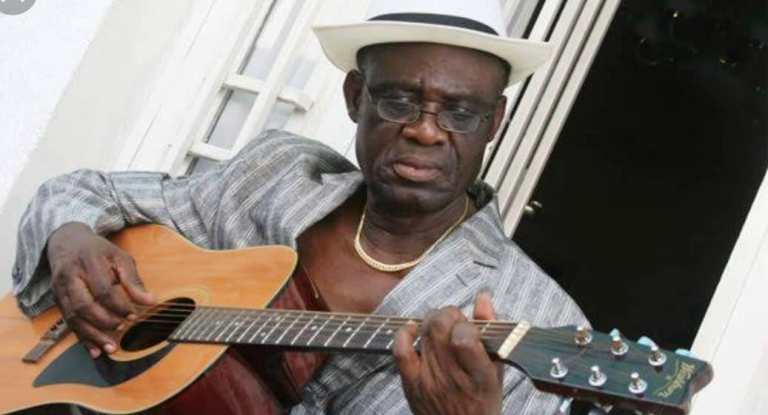 Simaro lutumba Ndomanueno jouant à la guitare coiffé d’un borsalino