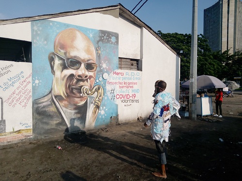 Eric Biansueki face au portrait de Manu Dibango lors de sa performance (Adiac)