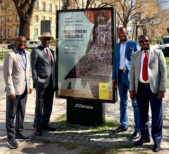 Délégation congolaise à Dresde posant devant une des affiches de l'exposition de Baudouin Mouanda