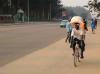 Une femme entrepreneuse sur une bicyclette avec un colis sur la tête